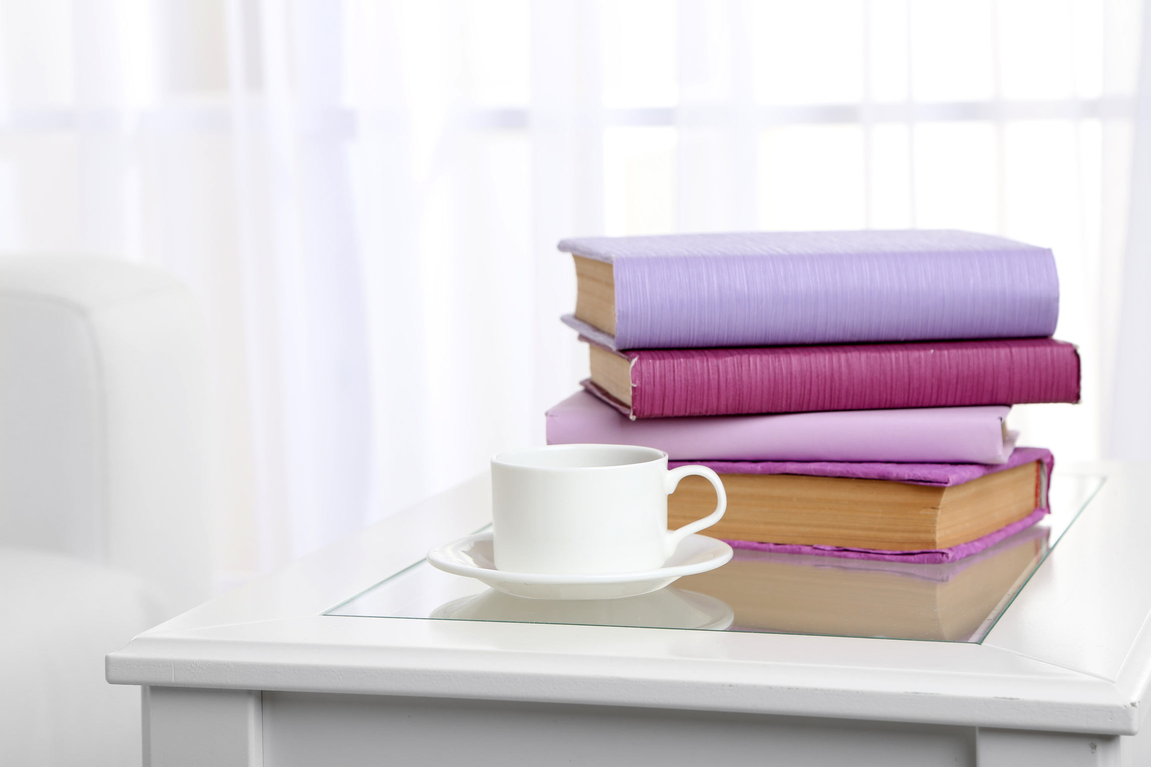 Pile of Purple Books with a Cup on a Table